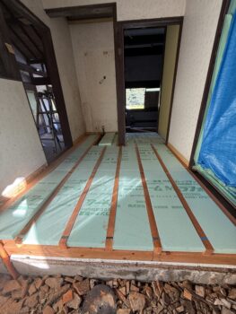 床下に緑色の押出法ポリスチレン断熱ボードを敷き詰めた施工中の様子。冷えを防ぐ断熱工事