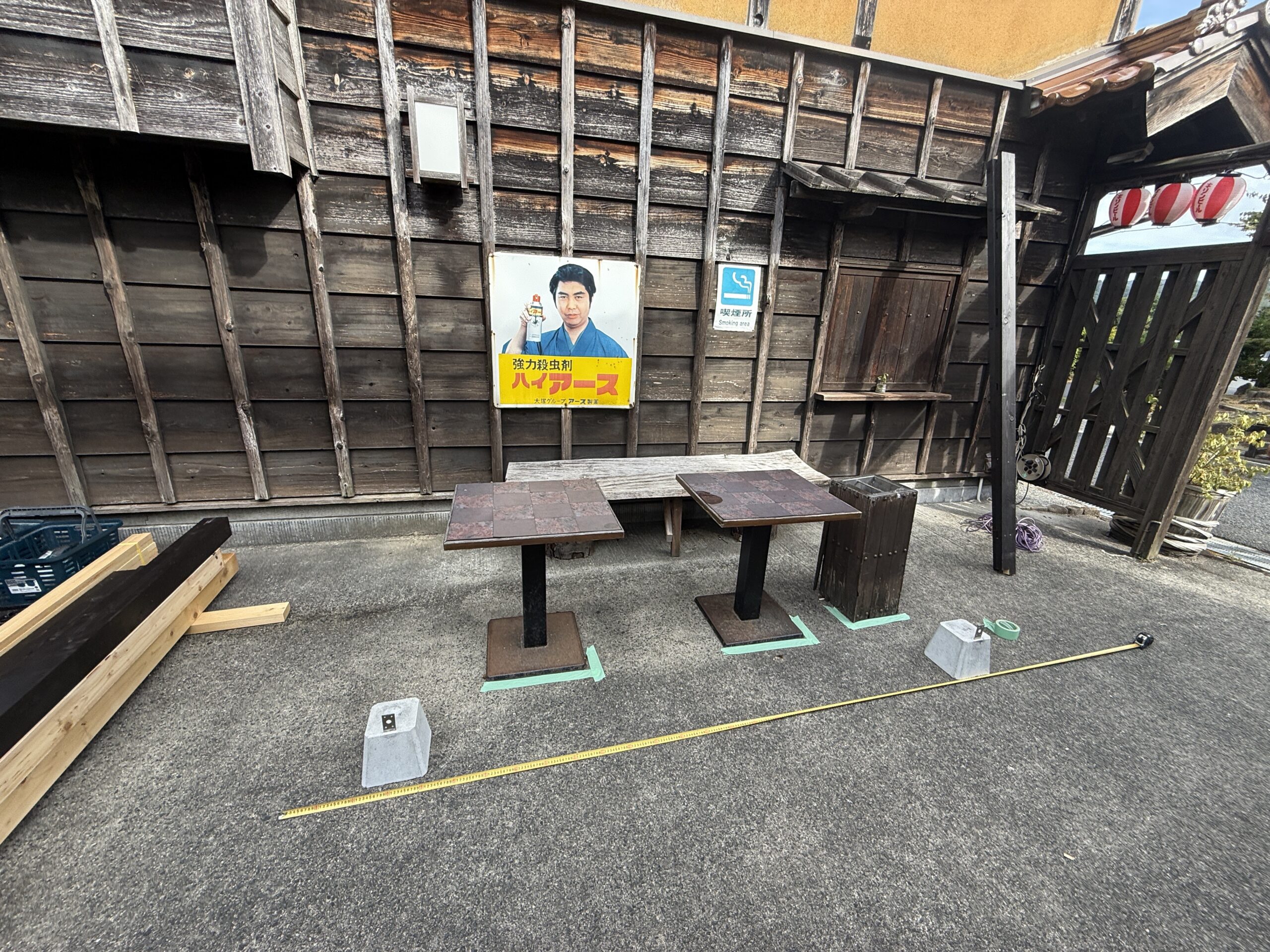 飲食店の喫煙所エリアに、雨よけ屋根を新設する準備。束石と資材が並ぶ