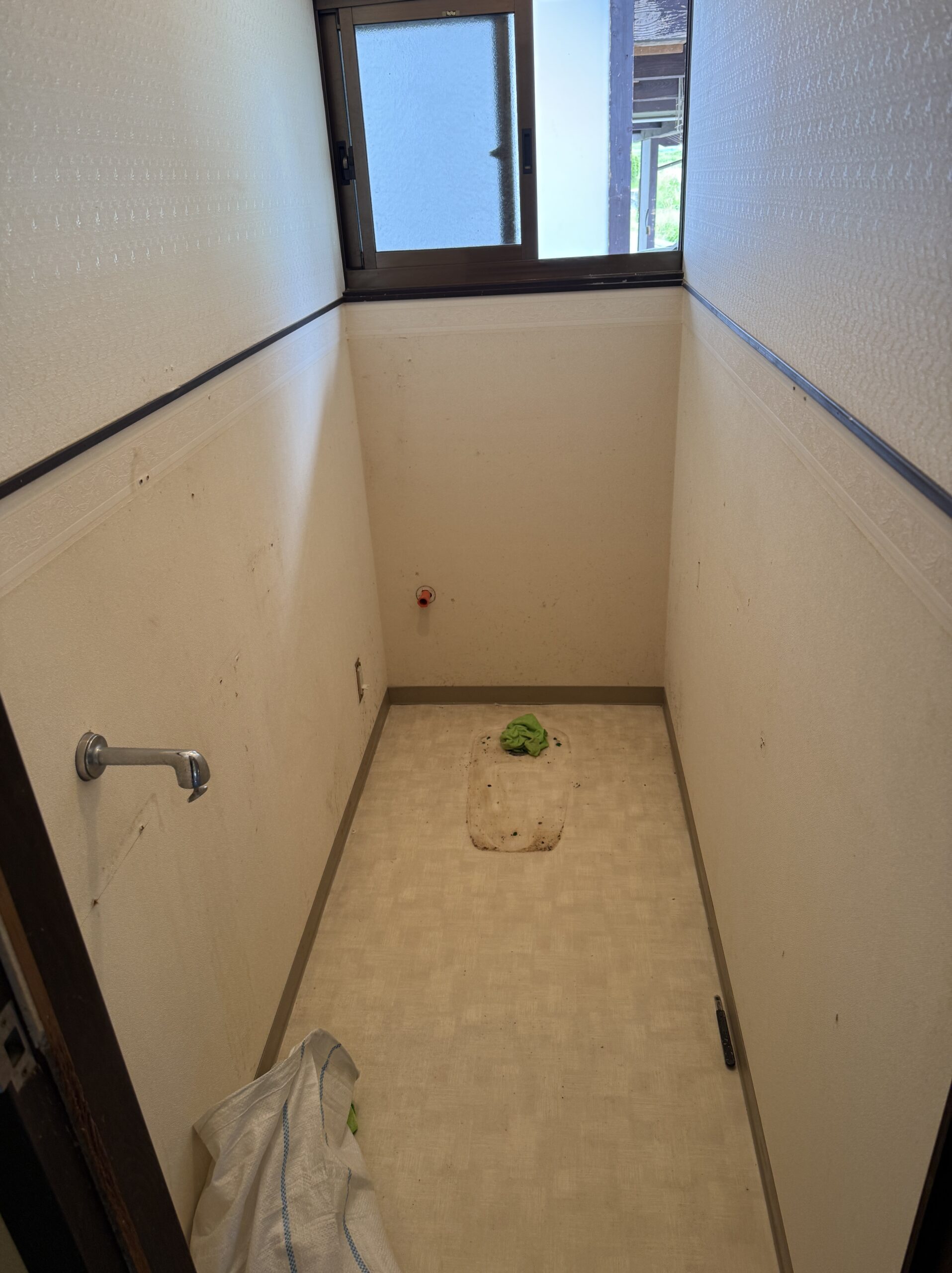 既存便器・手洗い・壁紙を撤去した直後の状態。給排水管が露出